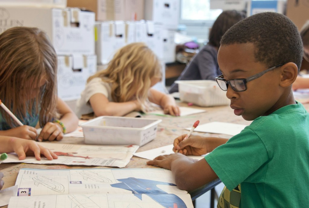 young children around a table working on an assignment in a classroom