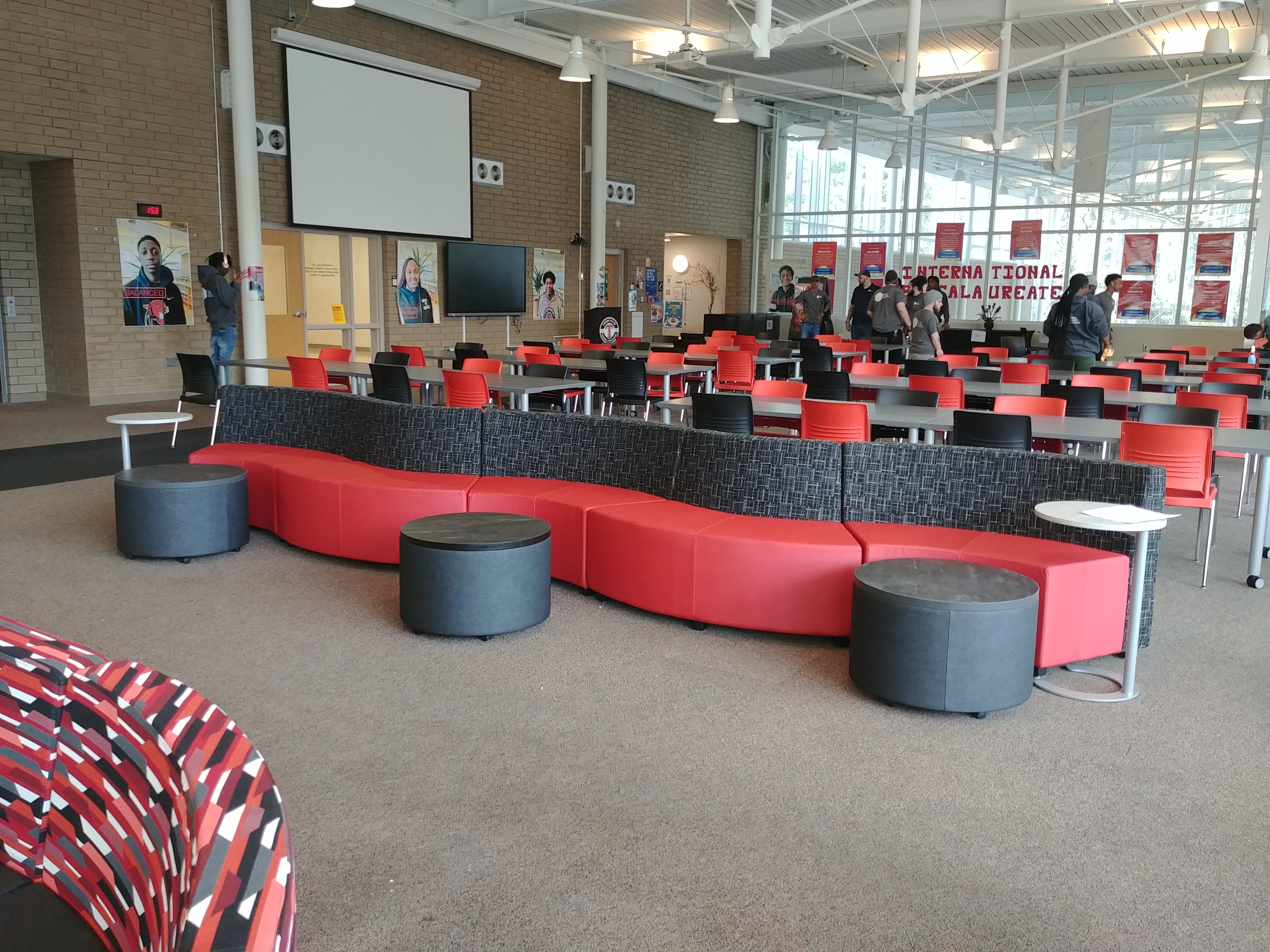 media center, red and black curvy sitting area with round black tables